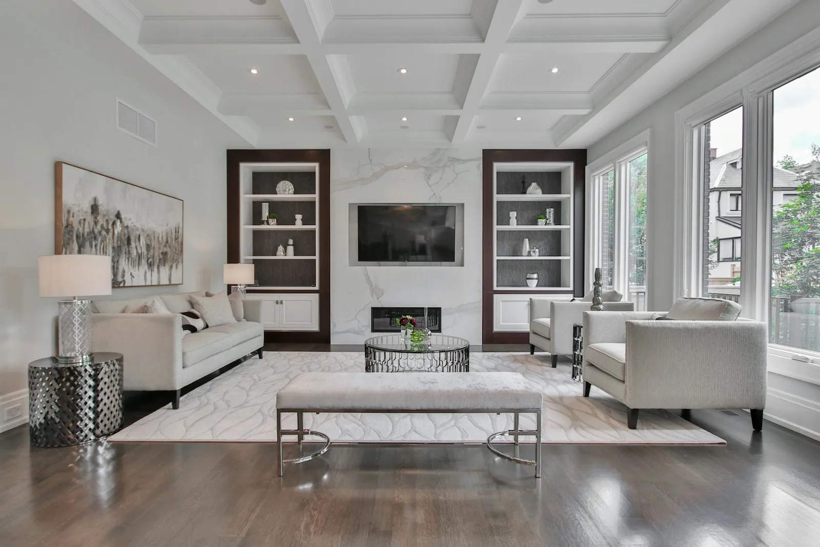 A bright living room with a marble fireplace, coffered ceiling, and freshly cleaned upholstery